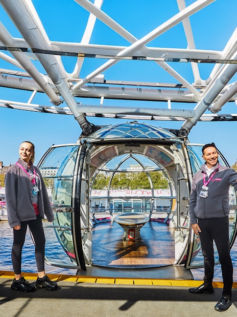 London Eye capsule entrance with staff welcoming visitors, view of Thames River.