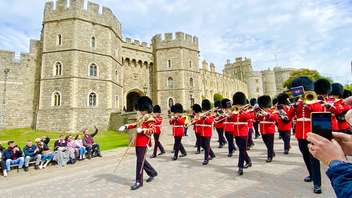 Guards in red uniforms marching at Windsor Castle during the Changing of the Guard ceremony.