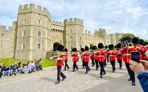 Guards in red uniforms marching at Windsor Castle during the Changing of the Guard ceremony.