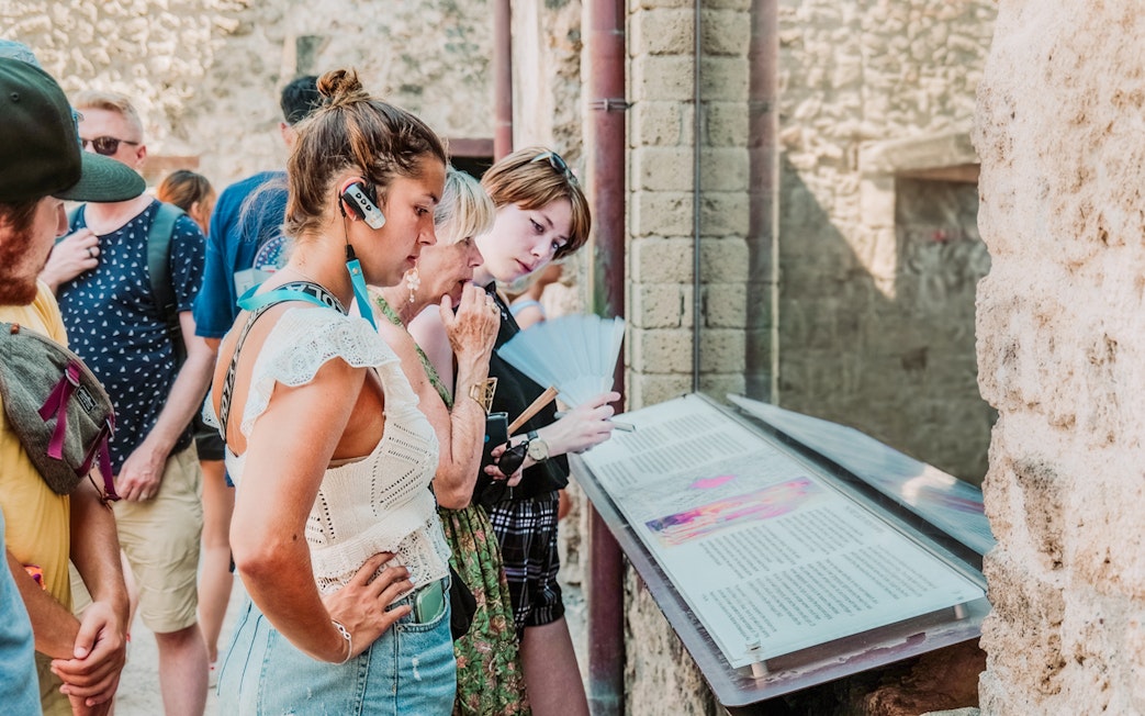 Tourists using audioguides at Pompeii archaeological site, Italy.