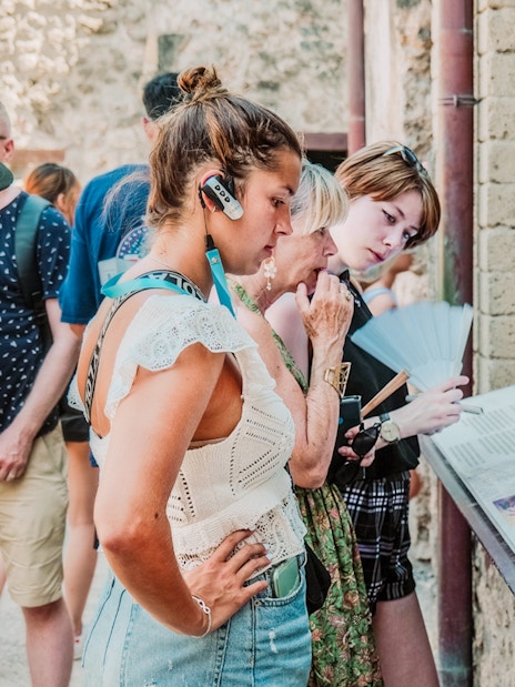 Tourists using audioguides at Pompeii archaeological site, Italy.
