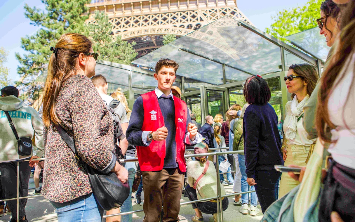 Guide leading a group on the Illumination Tour of Paris near the Eiffel Tower.