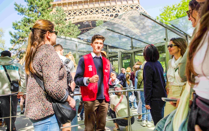 Guide leading a group on the Illumination Tour of Paris near the Eiffel Tower.