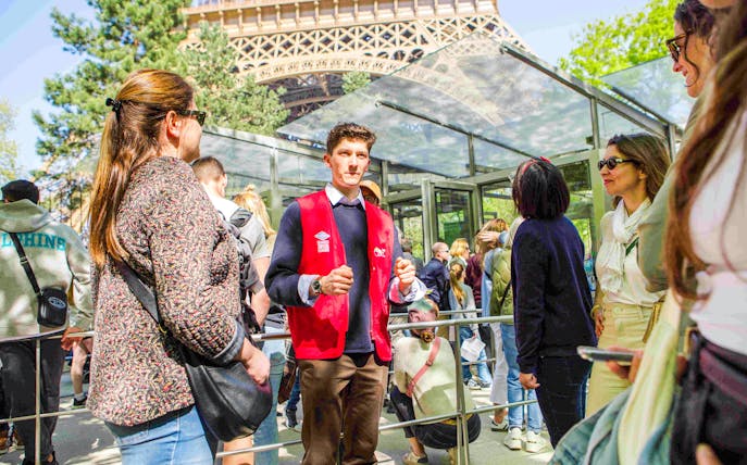 Guide leading a group on the Illumination Tour of Paris near the Eiffel Tower.