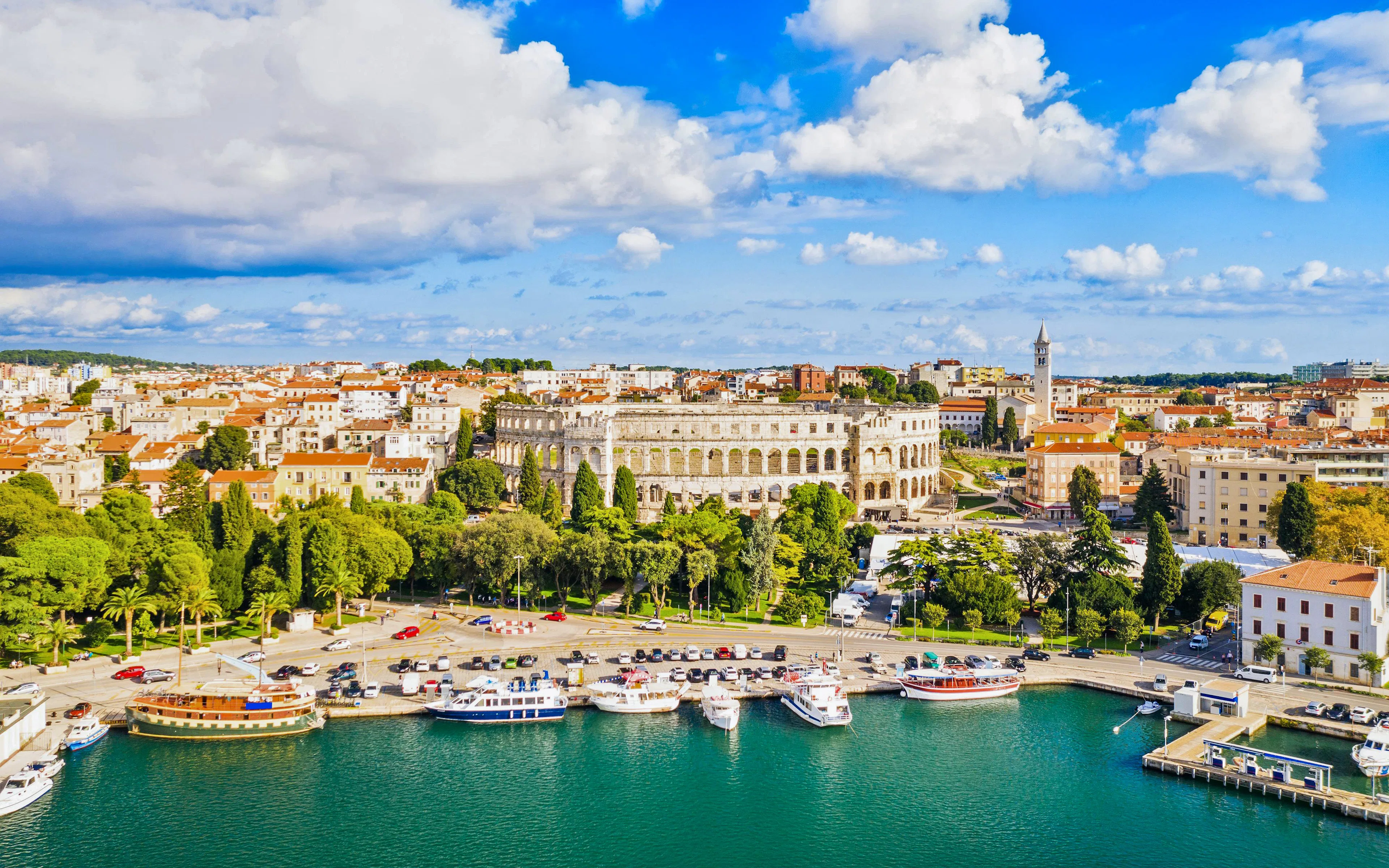 Aerial view of Pula's Roman Arena and Old Town Center, Croatia, with harbor and boats.