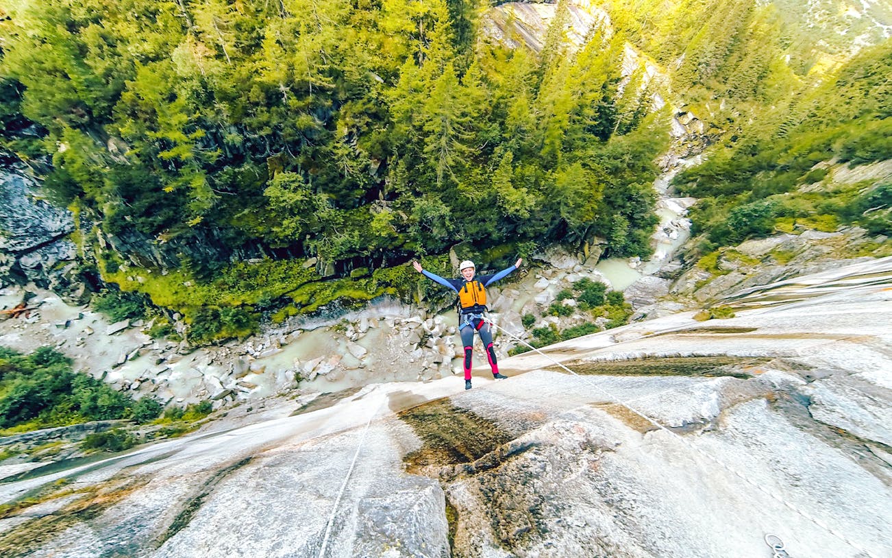 Adventurers canyoning through a narrow gorge in Interlaken, Switzerland, navigating waterfalls and rock formations.