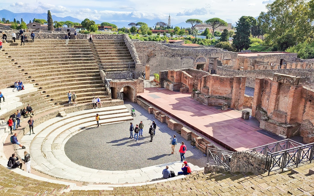 Visitors exploring the ancient amphitheatre in Pompeii, Italy.
