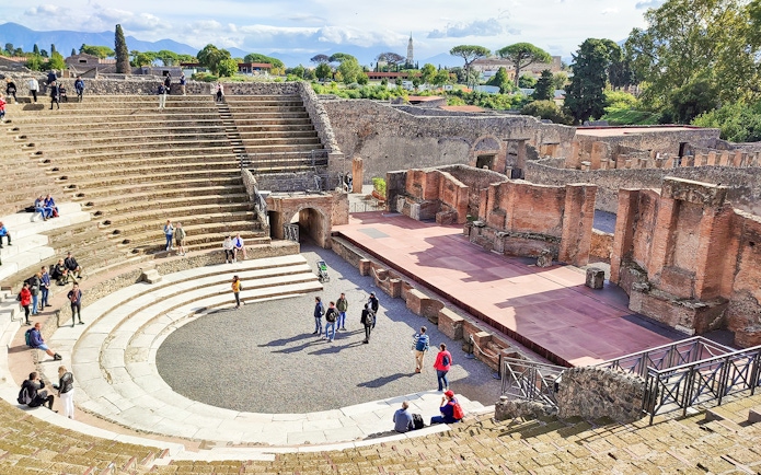 Visitors exploring the ancient amphitheatre in Pompeii, Italy.