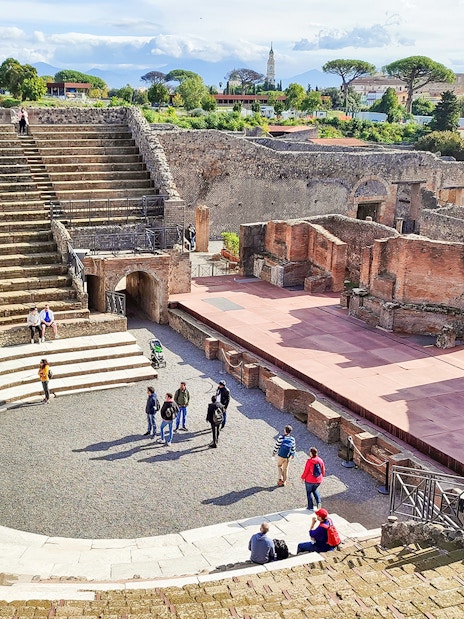 Visitors exploring the ancient amphitheatre in Pompeii, Italy.