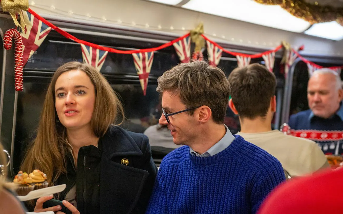 People enjoying festive treats on a London Christmas Lights & Bites Tour bus decorated with Union Jack bunting.
