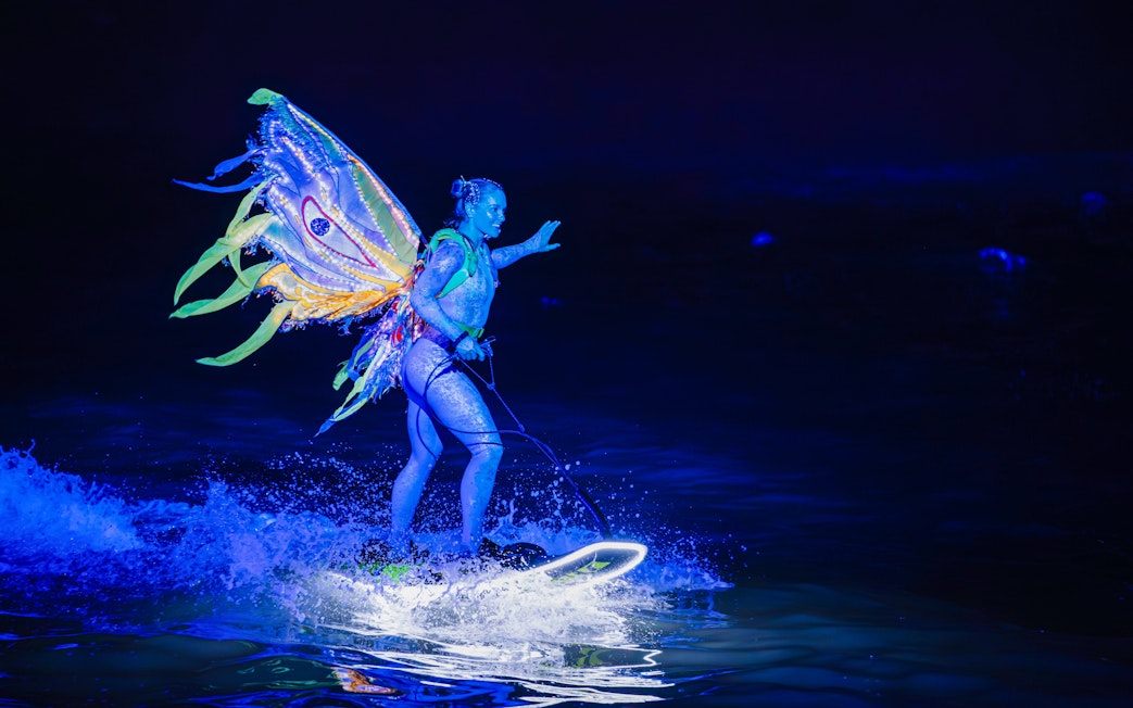 Performer with illuminated wings on water at Symphony of the Sea show.