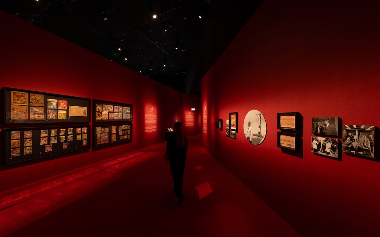 Exhibition hall with red walls displaying art and photographs at ArtScience Museum, Singapore.