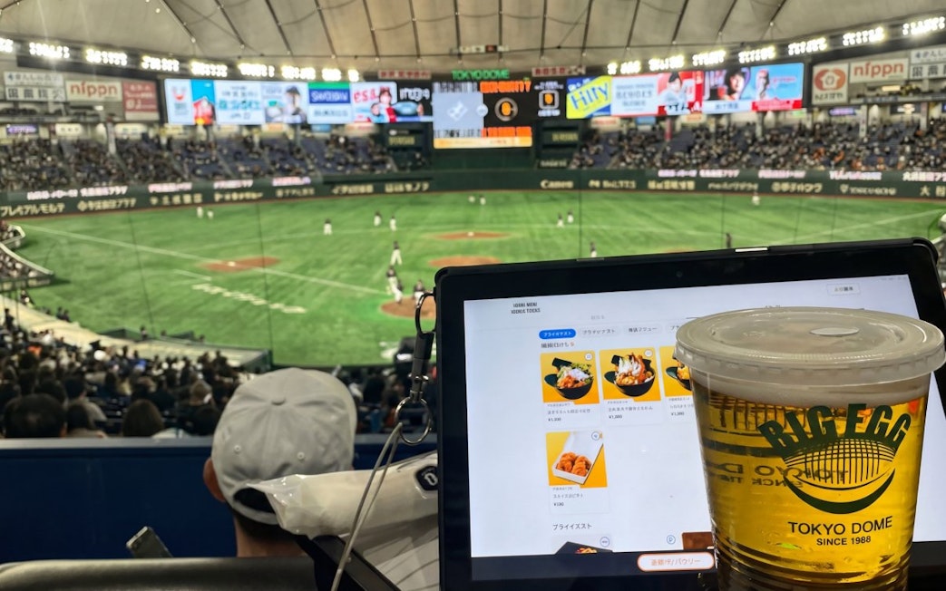 Baseball game at Tokyo Dome with a tablet menu and beer in the foreground.