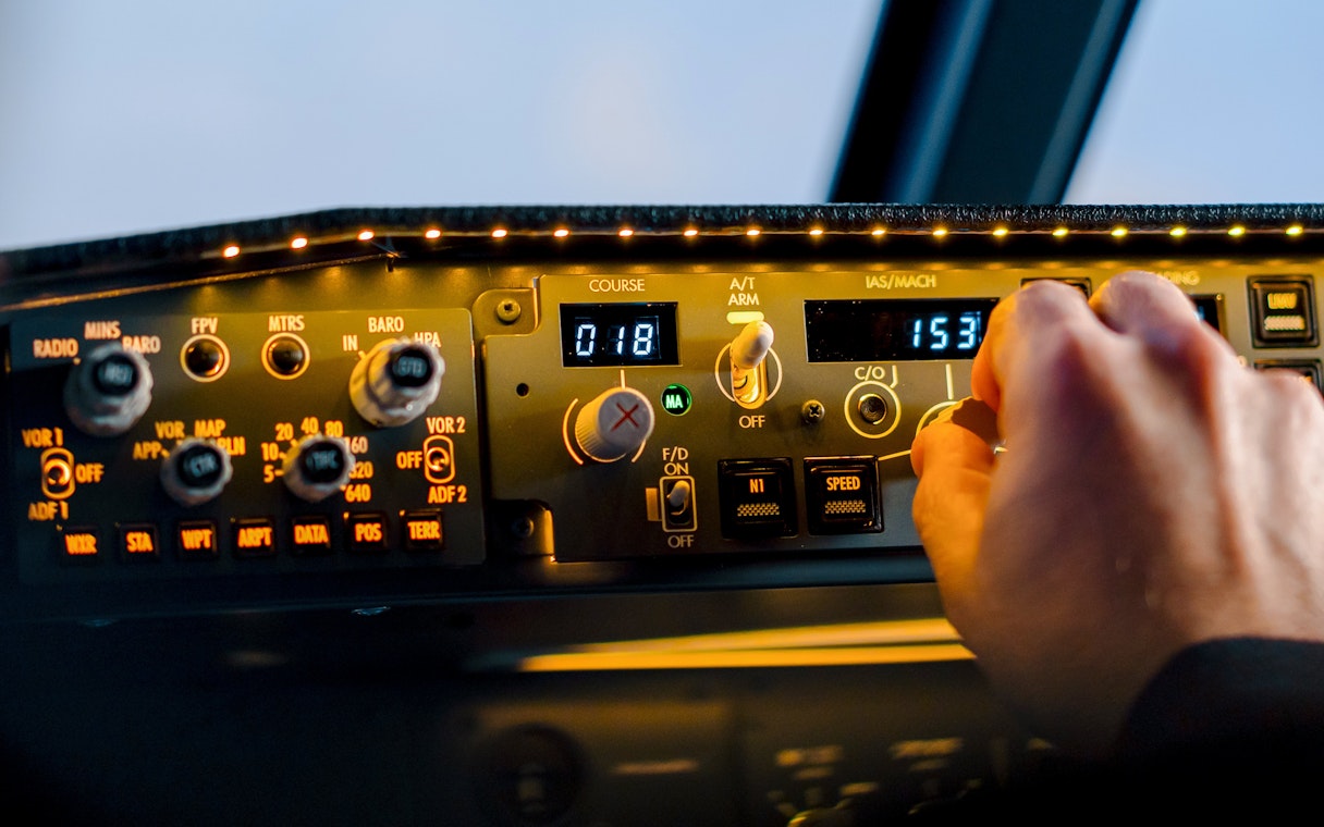Control panel in Boeing 737 flight simulator cockpit with hand adjusting settings.