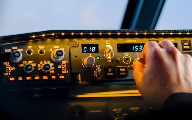 Control panel in Boeing 737 flight simulator cockpit with hand adjusting settings.