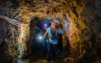 Tourists exploring a tunnel inside Fremantle Prison with helmets and flashlights.