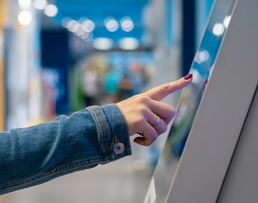 Person interacting with touchscreen in aquarium or museum.