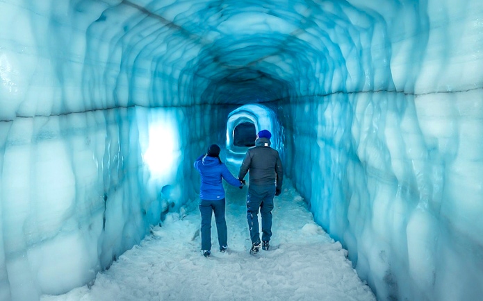 Guests walking inside the blue ice tunnel of Langjökull glacier.