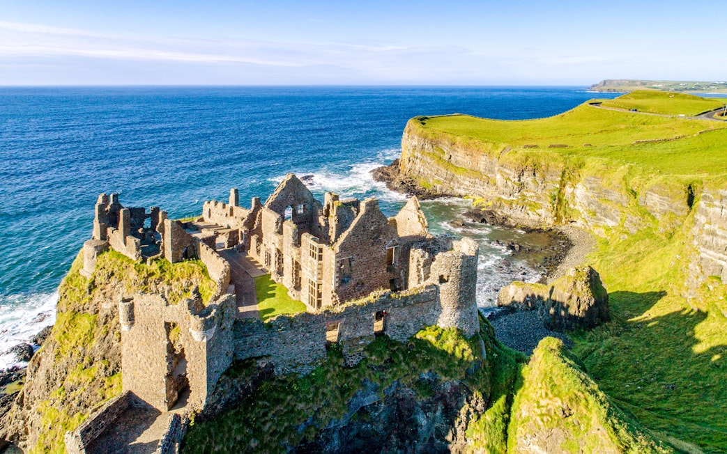 Dunluce Castle ruins on a coastal cliff in Northern Ireland with ocean view.