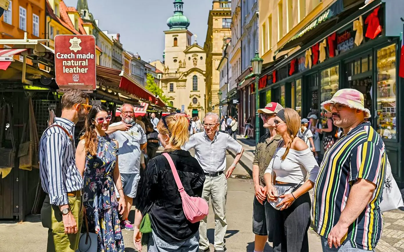 Tour group exploring a market street in Prague with historic architecture in the background.