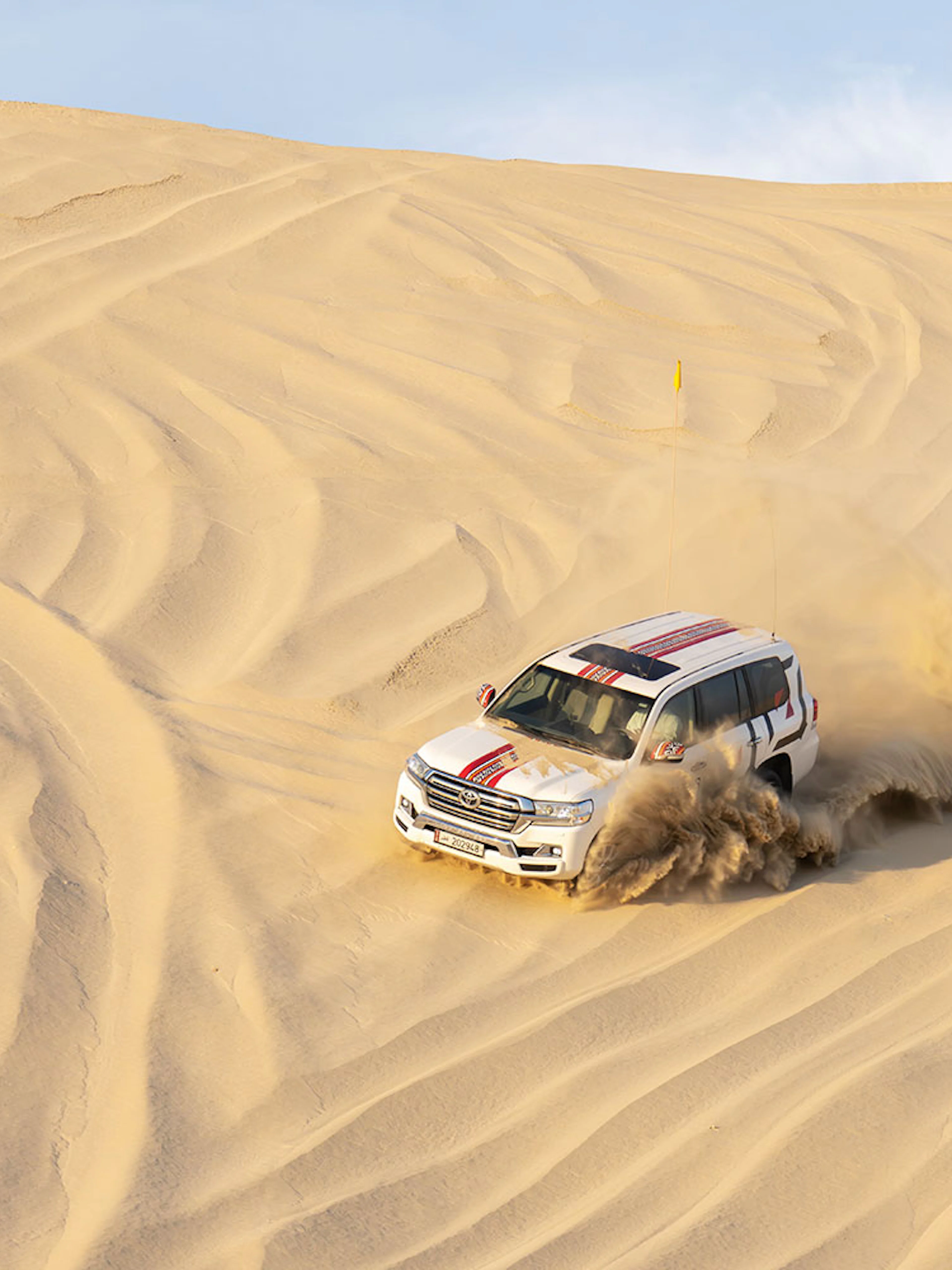 SUV driving through sand dunes on a desert safari in Doha.