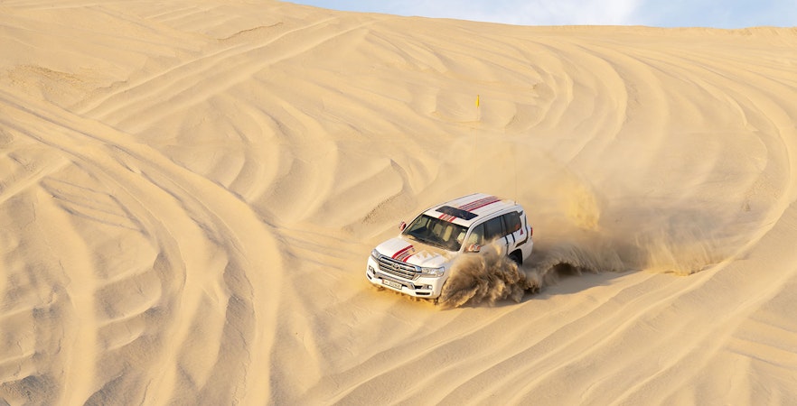 SUV driving through sand dunes on a desert safari in Doha.