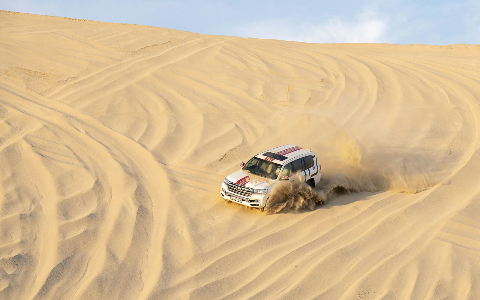 SUV driving through sand dunes on a desert safari in Doha.