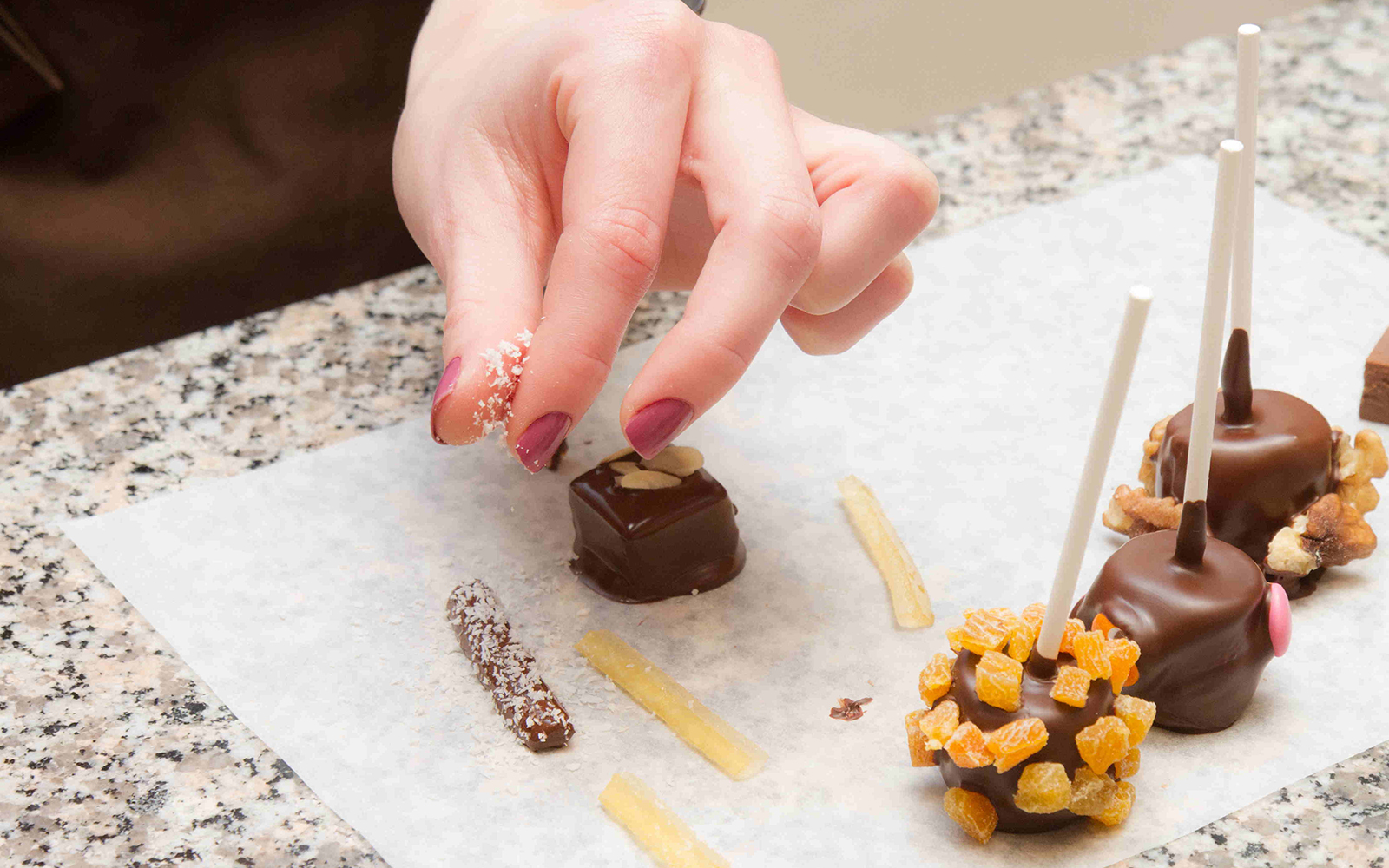 Hand decorating chocolates with toppings at Choco-Story Paris.