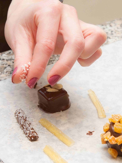 Hand decorating chocolates with toppings at Choco-Story Paris.