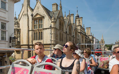Open-top bus tour passing historic buildings in Oxford.