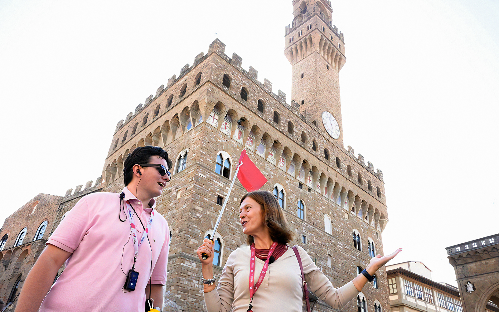 Tour guide with a red flag leading a group in front of Palazzo Vecchio, Florence.
