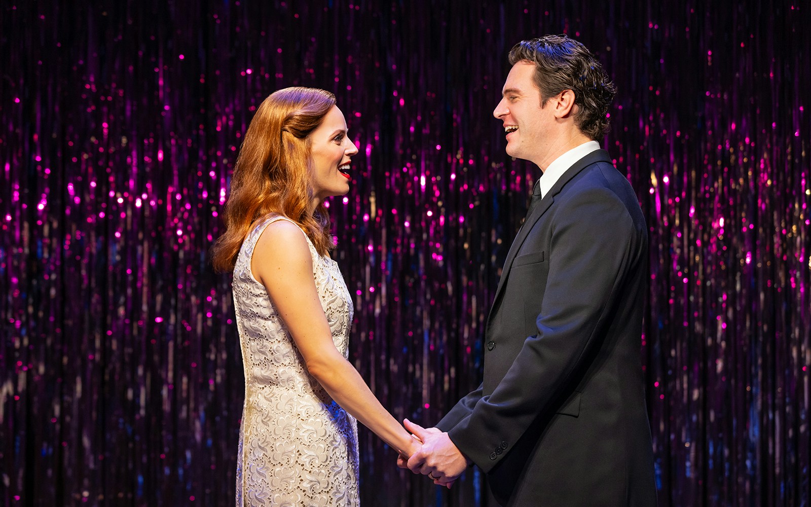 Two performers holding hands on stage during "Merrily We Roll Along" musical.