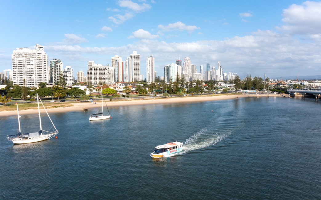 Aquaduck boat cruising on a river with city skyline in the background, Gold Coast.