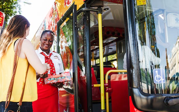 Woman boarding hop-on hop-off bus with ticket in hand.