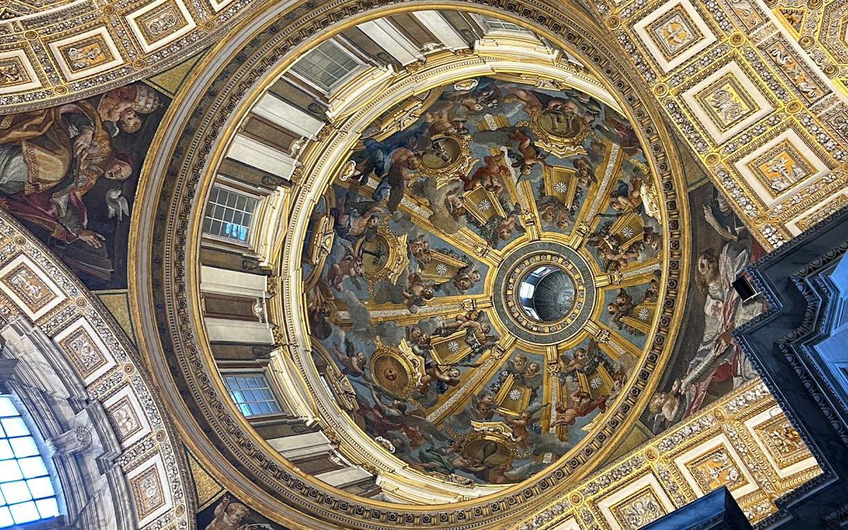 St. Peter's Basilica dome interior with intricate frescoes and gold detailing, Vatican City.