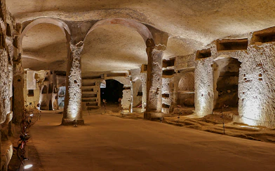 Exploring the ancient Catacombs of San Gennaro in Naples, Italy, with illuminated arches and tombs.