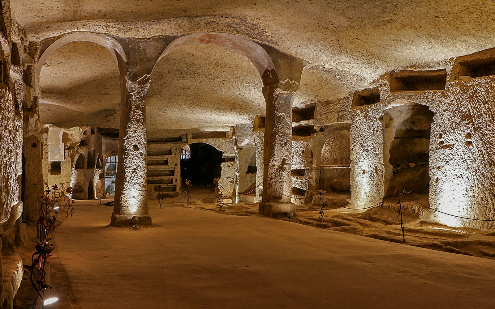 Exploring the ancient Catacombs of San Gennaro in Naples, Italy, with illuminated arches and tombs.