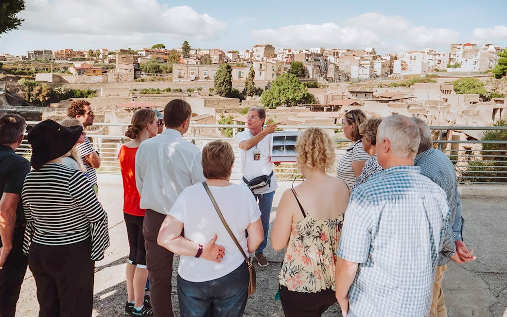 Archaeologist explaining Herculaneum ruins to tourists in Naples, Italy.