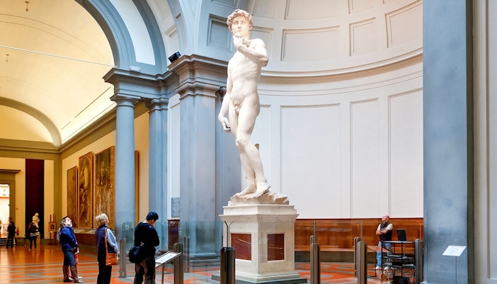 Statue of Michelangelo's David at Accademia Gallery, Florence, with visitors observing.