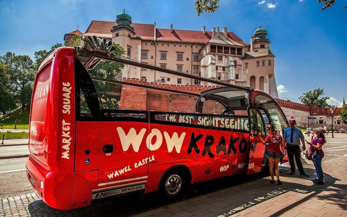 Kraków hop-on hop-off bus near Wawel Castle with tourists boarding.