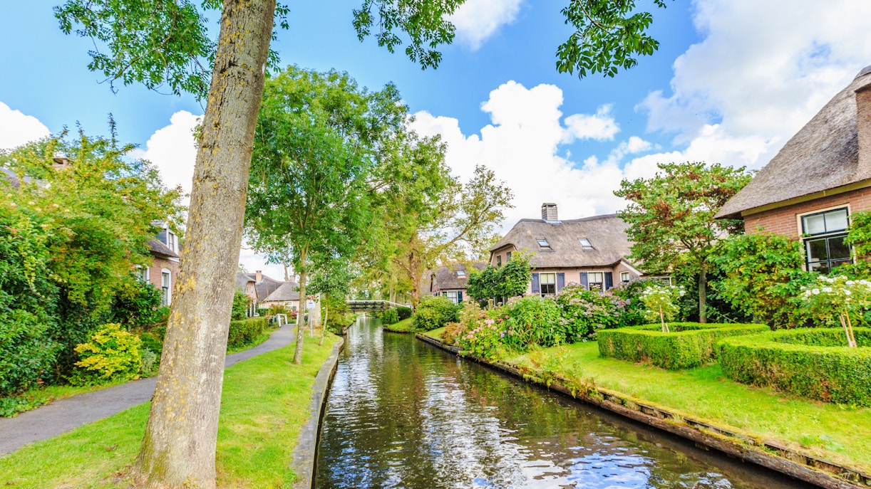Canal view in Giethoorn, Amsterdam with traditional houses and lush greenery.