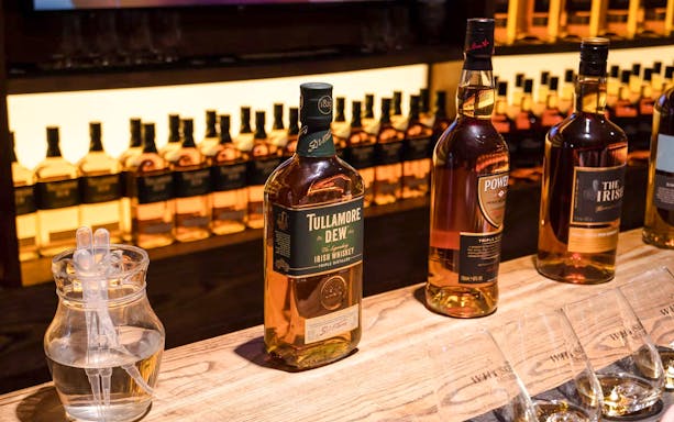 Bottles displayed at Irish Whiskey Museum, Dublin, showcasing various whiskey brands.