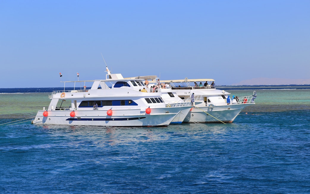 Motor yachts anchored in the Red Sea, Hurghada, with passengers on deck.