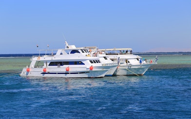 Motor yachts anchored in the Red Sea, Hurghada, with passengers on deck.