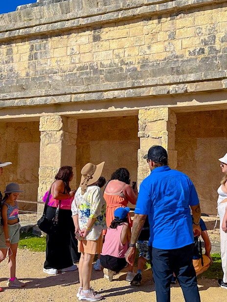 Tourists exploring ancient structures at Chichen Itza during sunrise.
