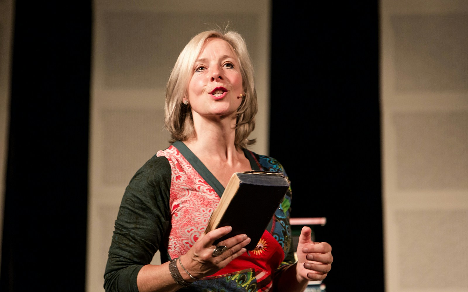 Storyteller performing "I Believe In Unicorns" on stage with a book in hand.