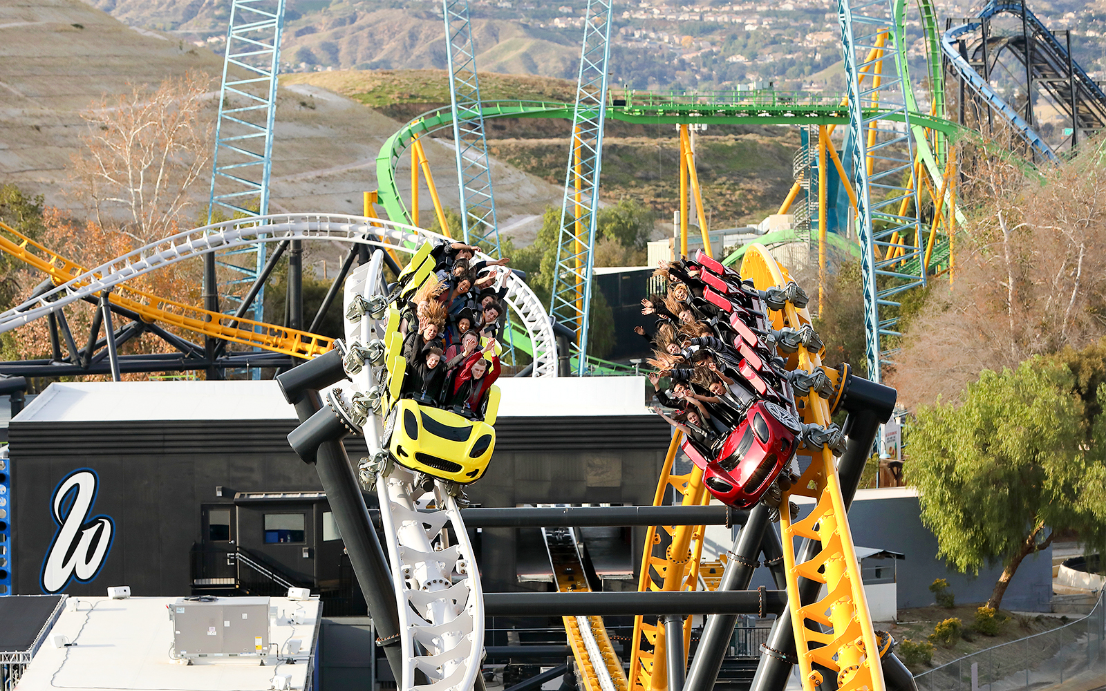 Roller coasters racing at Six Flags Magic Mountain's West Coast Racers with riders enjoying the thrill.