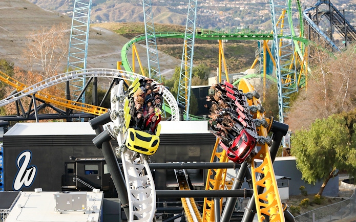 Roller coasters racing at Six Flags Magic Mountain's West Coast Racers with riders enjoying the thrill.