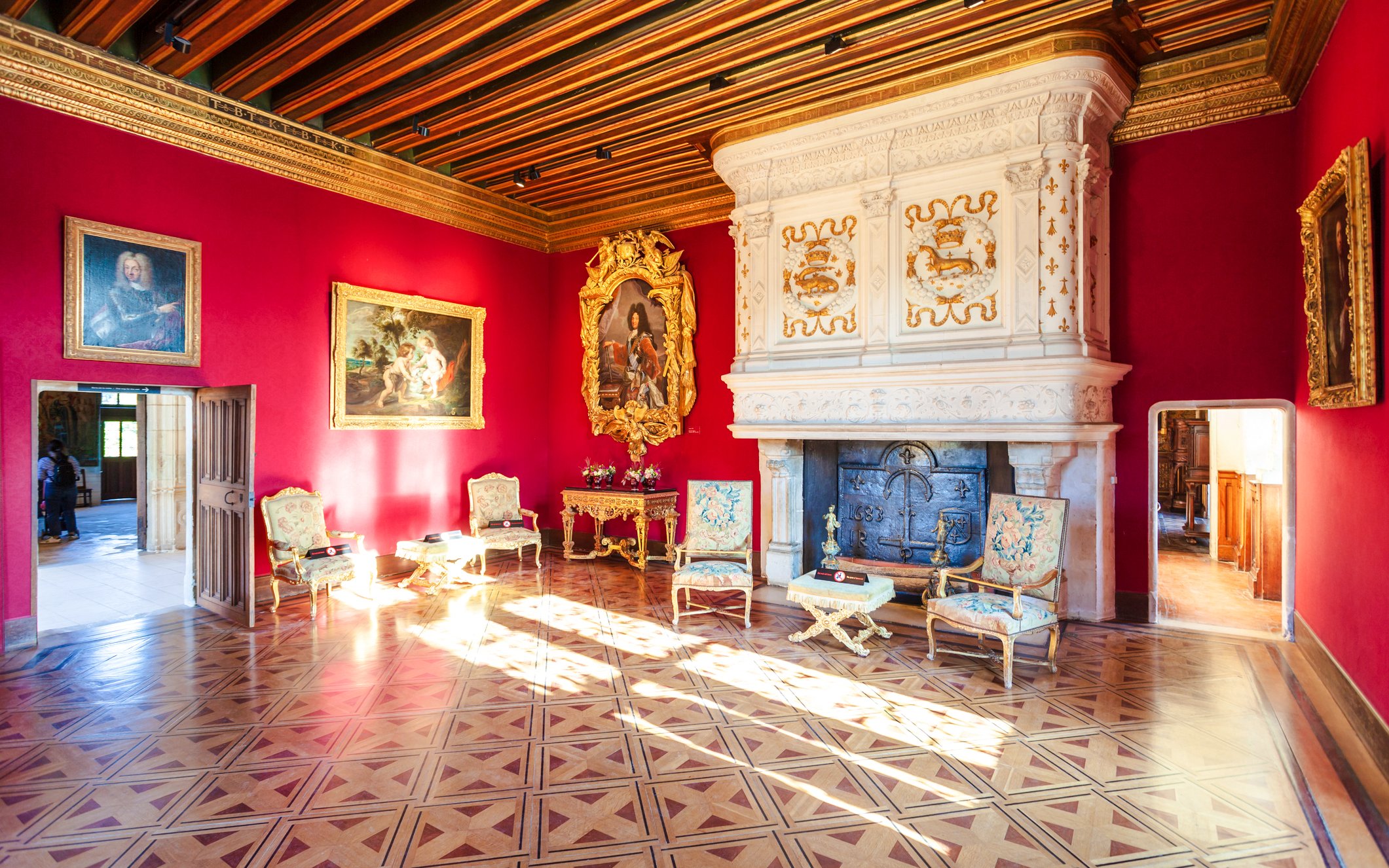 Château de Chenonceau interior with ornate fireplace and red walls, Loire Valley, France.