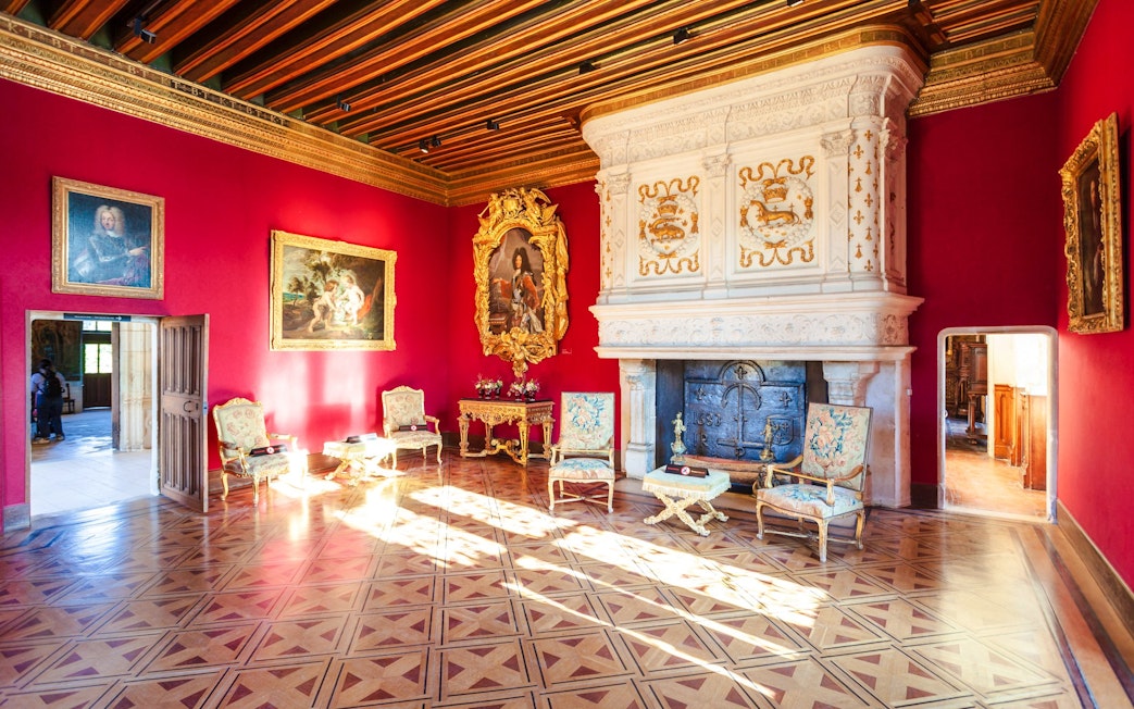 Château de Chenonceau interior with ornate fireplace and red walls, Loire Valley, France.